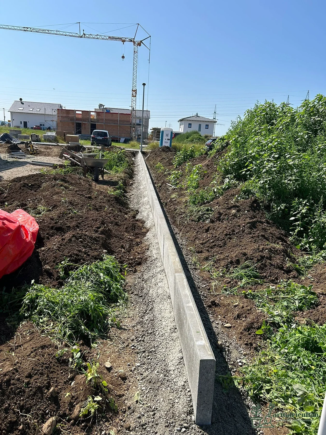 Baustelle mit Gartenmauer und vorbereiteten Beeten