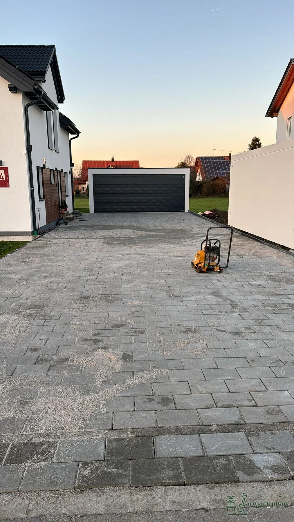 Hofeinfahrt mit dunklem Pflaster vor einer Garage