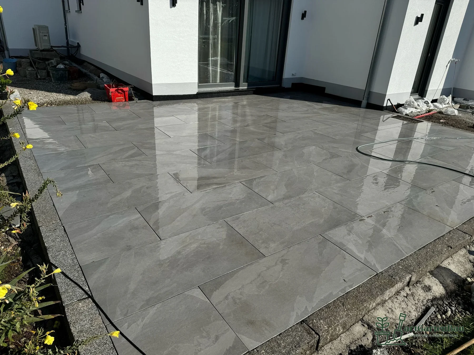 Moderne Terrasse mit glänzenden grauen Platten von artGartenBau