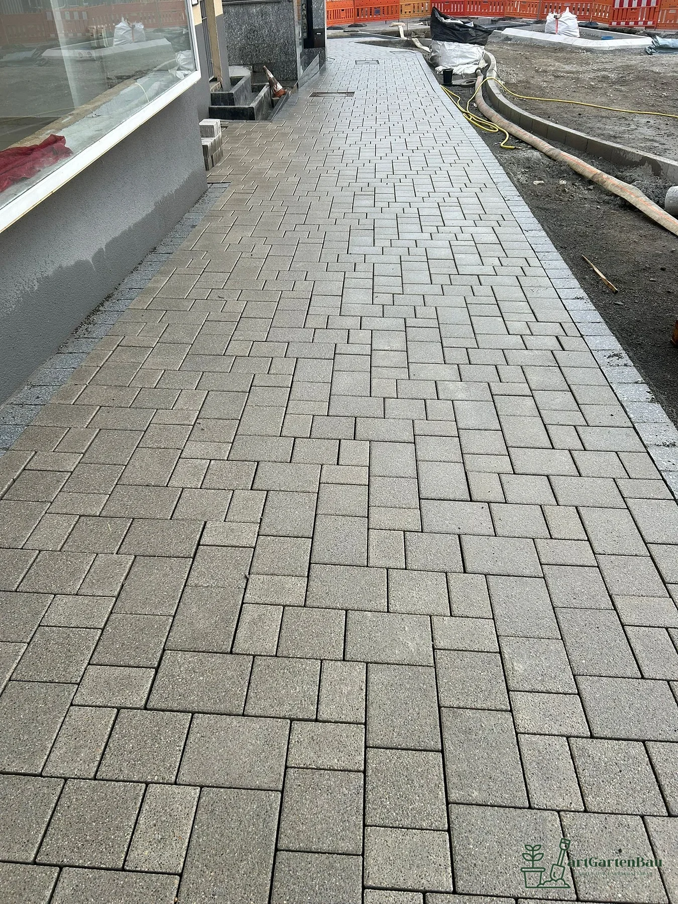 Gerader Gehweg aus Betonpflaster entlang eines Hauses