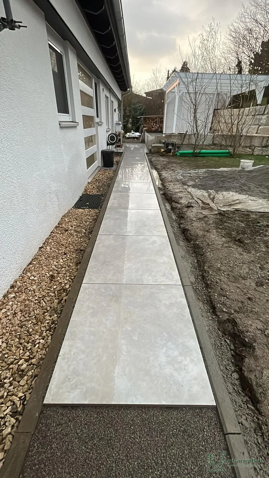 Schmaler Seitenweg mit Betonplatten und Kiesstreifen