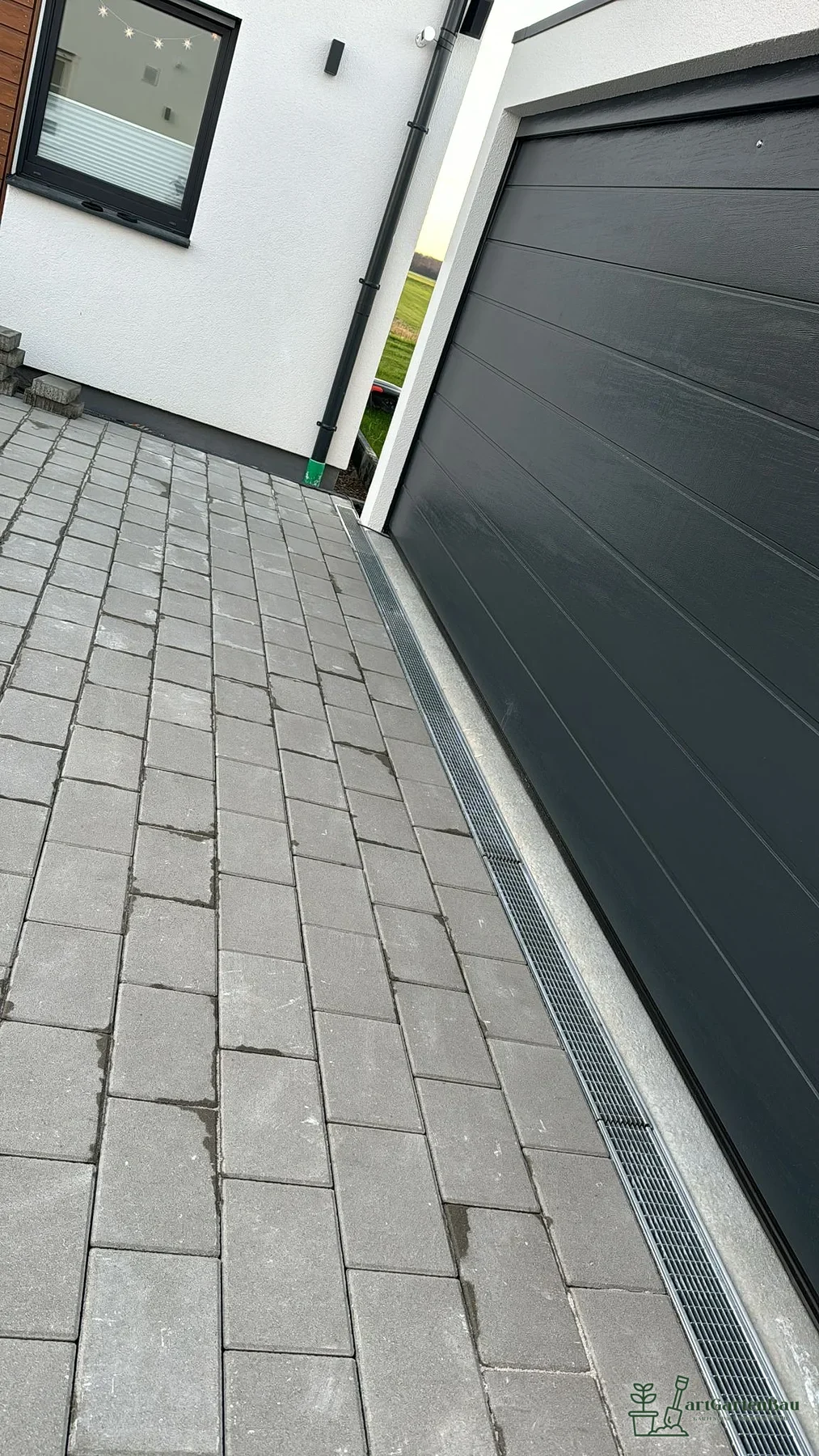 Schmale Garagenzufahrt mit sauber verlegtem Betonpflaster