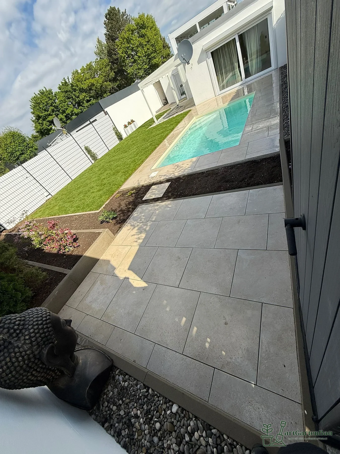Seitliche Ansicht einer Poolterrasse mit Gartenfläche